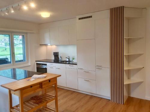 cocina con armarios blancos y mesa de madera en Apartment La Riva by Interhome en Laax