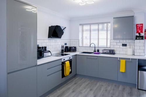een keuken met witte en blauwe kasten en gele handdoeken bij Cosy Luxurious 3-Bedroom Home in Birmingham