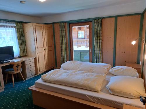 a bedroom with two beds and a desk and a television at Apartment Gratzerhof-2 by Interhome in Finkenberg