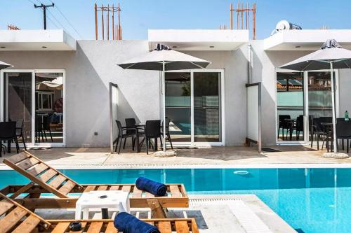 a pool with chairs and umbrellas next to a house at Papatsas Center Houses in Nydri