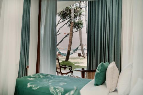 a bedroom with a bed and a view of the beach at Mosvold Villa in Ahangama