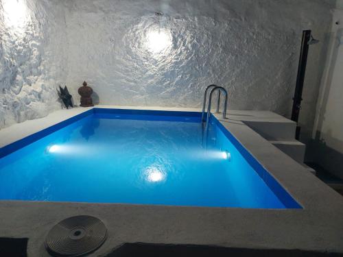 uma piscina azul num quarto com escadas em Casa rural El Patio em Benadalid