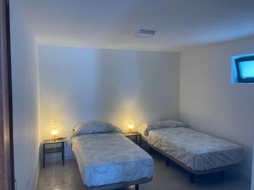 two beds in a room with two lamps on tables at El Marinero, piso 2 y piso 3 in La Santa