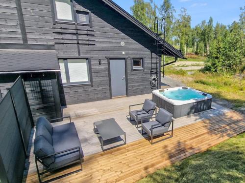 a deck with chairs and a hot tub next to a house at Holiday Home Himoksen keiju 2 by Interhome in Jämsä