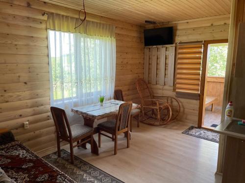 a dining room with a table and chairs in a cabin at AVALON - Котедж на озері in Borysxaw