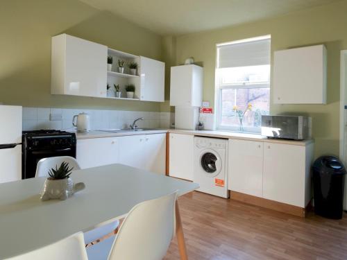 a kitchen with white cabinets and a table at Pass the Keys City centre in Doncaster