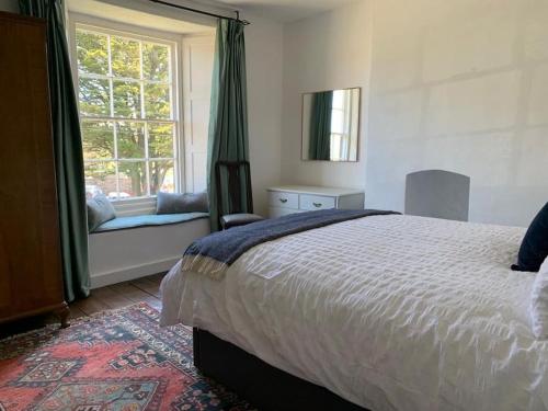 a bedroom with a large bed and a window at Lovely Cottage beside Surf Beaches & Bude Canal in Bude