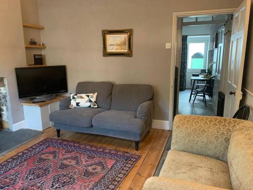 a living room with a couch and a tv at Lovely Cottage beside Surf Beaches & Bude Canal in Bude