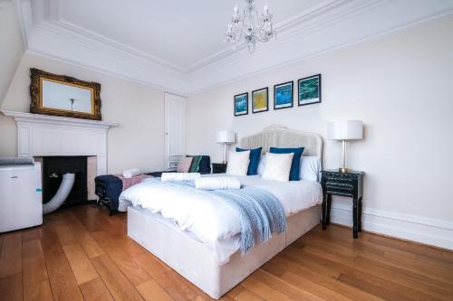 a white bedroom with a large bed and a fireplace at Harrods Knightsbridge Flat in Central KB89 in London