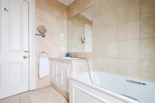 La salle de bains blanche est pourvue d'une baignoire et d'un lavabo. dans l'établissement Harrods Knightsbridge Flat in Central KB89, à Londres