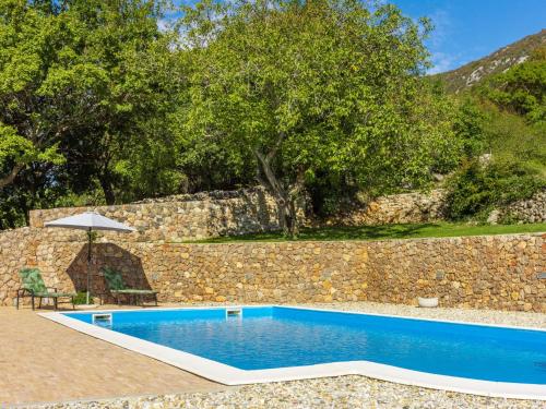 a swimming pool in front of a stone wall at Holiday Home Lukata by Interhome in Drivenik