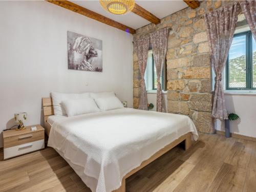 a bedroom with a large bed and a stone wall at Holiday Home Lukata by Interhome in Drivenik