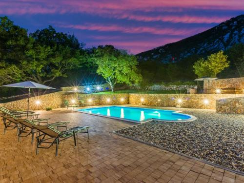 a pool with chairs and an umbrella at night at Holiday Home Lukata by Interhome in Drivenik