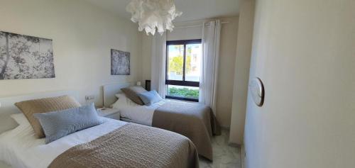 um quarto com duas camas e uma janela em La Alcaidesa Valerie Bruno em San Roque