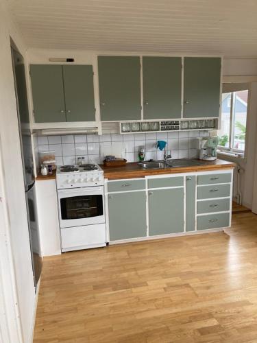 une cuisine avec des appareils électroménagers blancs et des armoires vertes dans l'établissement BB Snäckan Hönö, à Hönö