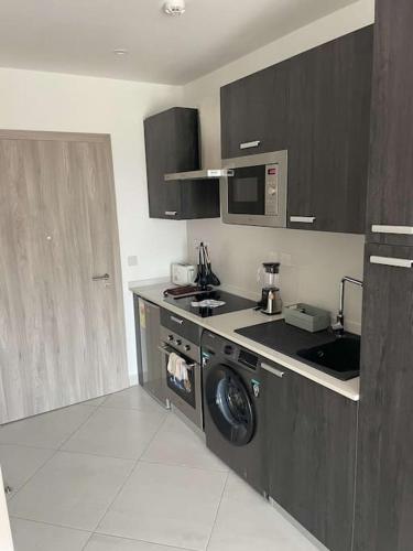 a kitchen with a sink and a washing machine at Studio unit @ Airport The Lennox in Accra