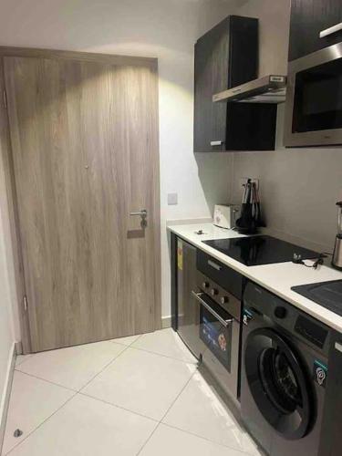 a kitchen with a washing machine and a wooden door at Studio unit @ Airport The Lennox in Accra