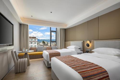 een hotelkamer met twee bedden en een groot raam bij Lijiang Ancient City Kasion purey Hotel - Big waterwheel store in Lijiang