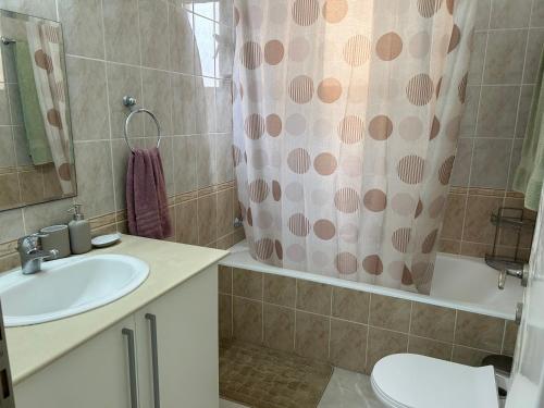 a bathroom with a sink and a shower curtain at Holiday Mandria apt with pool in Paphos