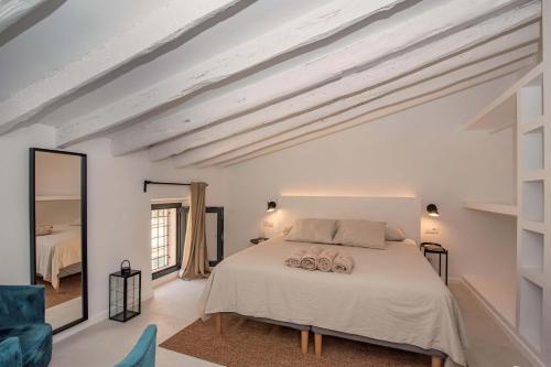 ein weißes Schlafzimmer mit einem Bett und einem Spiegel in der Unterkunft Helen House in Porreres