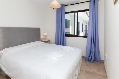 1 dormitorio con 1 cama blanca grande y cortinas azules en 2066-Apt 2 bedrooms on beach, tenis, gym, pool, en Manilva