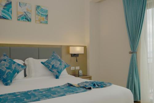 a bedroom with a bed with blue and white pillows at Stay Easy Plus Hotel in Addis Ababa