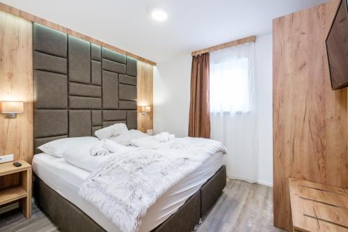 een slaapkamer met een groot bed met een houten hoofdeinde bij TOP 8 Apartment - Zell am See - Kaprun in Piesendorf