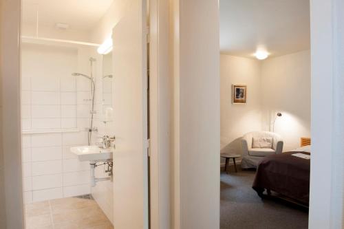 a bathroom with a shower and a sink and a bed at Benniksgaard Anneks in Gråsten