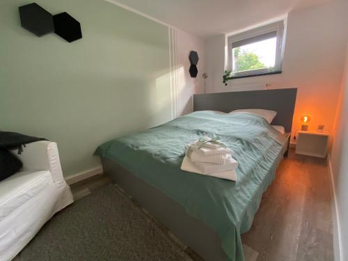 a bedroom with a bed with green sheets and a window at Apartment 'BB43' - 70qm mit Terrasse und kleinem Garten am Rande der Eifel in Düren - Eifel