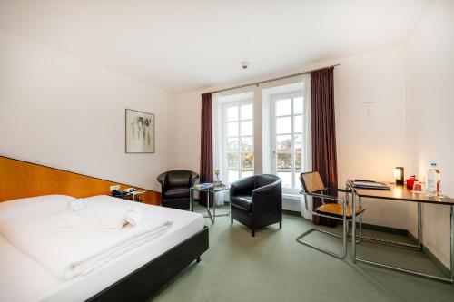 ein Hotelzimmer mit einem Bett, einem Schreibtisch und Stühlen in der Unterkunft Schloss Lautrach in Lautrach