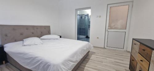 a bedroom with a large white bed and a dresser at Casa Emy in Râmnicu Vâlcea