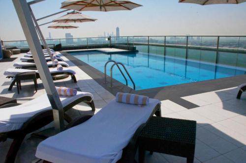 - une piscine avec des chaises et des parasols dans un bâtiment dans l'établissement Park Regis Kris Kin Hotel, à Dubaï