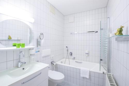 een witte badkamer met een wastafel, een bad en een toilet bij Hotel Schloss Nebra in Nebra
