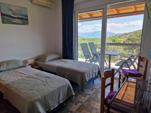 a room with two beds and a balcony with a table and chairs at Grieks vakantiehuis To Kalokairi in Kalamákion