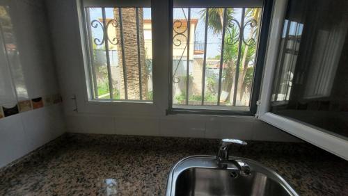 a sink in a bathroom with two windows at Casita de invitados en Otura in Otura