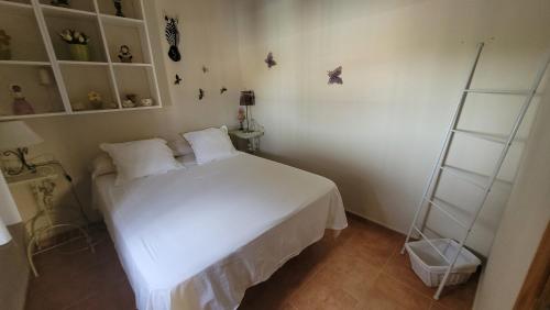 a small bedroom with a white bed and shelves at Casita de invitados en Otura in Otura