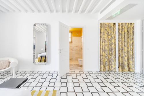 uma casa de banho branca com piso em azulejo branco e uma porta em ANEMI Folegandros em Karavostasi