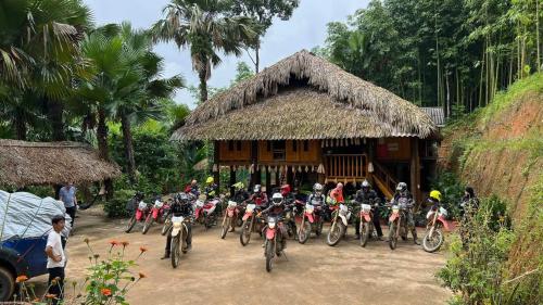um grupo de pessoas a andar de bicicleta em frente a uma cabana em Vu Linh Palm House Homestay - Bungalow em Yen Bai
