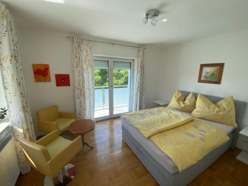 a bedroom with a bed and a chair and a window at Ferienwohnung Nussbaumblick in Ottensheim