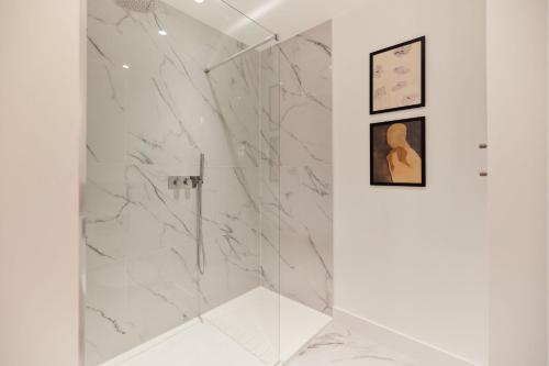 La salle de bains est pourvue d'une douche et de murs en marbre. dans l'établissement The Banfield Park Wonder - Lovely 3BDR Flat with Parking and Patio, à Londres