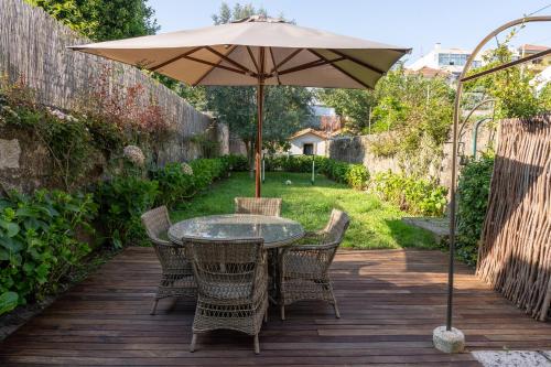 Porto Premium Villa في بورتو: طاولة وكراسي مع مظلة على سطح خشبي