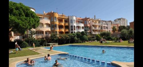 a group of people in a large swimming pool with buildings at Apartamento El olivo in Empuriabrava