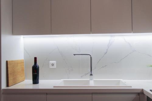 a white kitchen with a sink and a bottle of wine at Phos Luxury Apartment in Lefkada