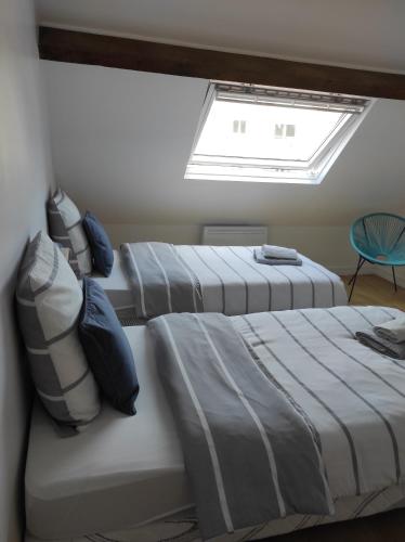 - 3 lits dans une chambre avec une lucarne dans l'établissement Charmant duplex à 2 pas de la plage, à Le Portel