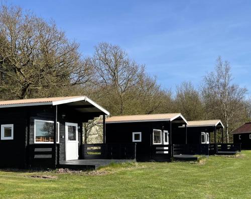 une maison noire avec une terrasse couverte et une pelouse dans l'établissement Myrhoj Camping, à Myrhøj