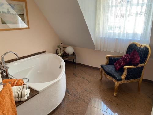 uma casa de banho com uma banheira grande e uma cadeira. em PARADISE GARDEN em Bad Sooden-Allendorf
