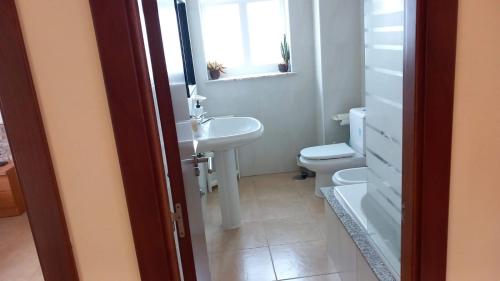 uma casa de banho com um lavatório, um WC e uma janela. em Beiramar2 em Muxía