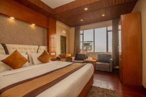 a bedroom with a large bed and a large window at Hotel Himalayan Retreat in Darjeeling