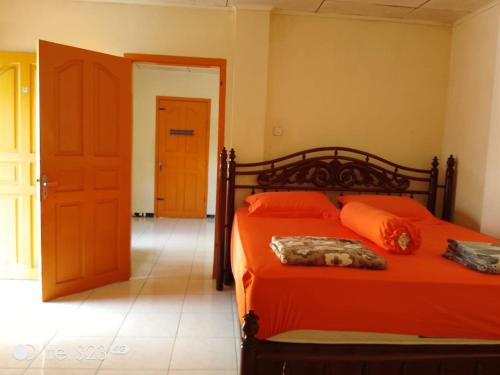 a bedroom with an orange bed with orange pillows at PONDOK SITI RAWIYAH Guest House in Bukittinggi