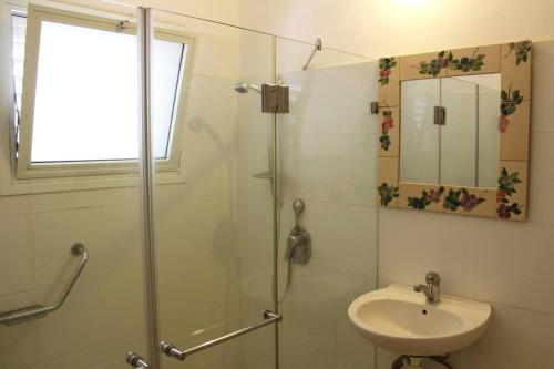 La salle de bains est pourvue d'une douche, d'un lavabo et d'un miroir. dans l'établissement VINTAGE FLAT STEPS FROM THE BEACH, à Tel Aviv